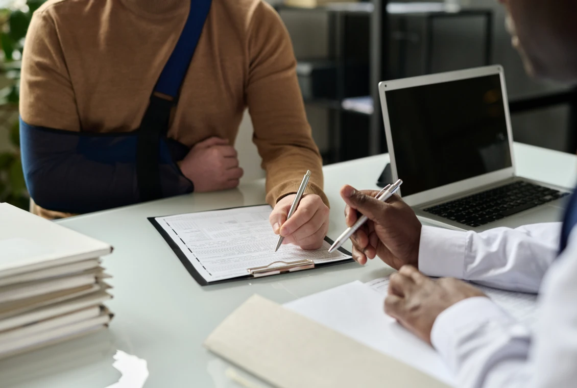 Office discussion with arm-in-sling individual
