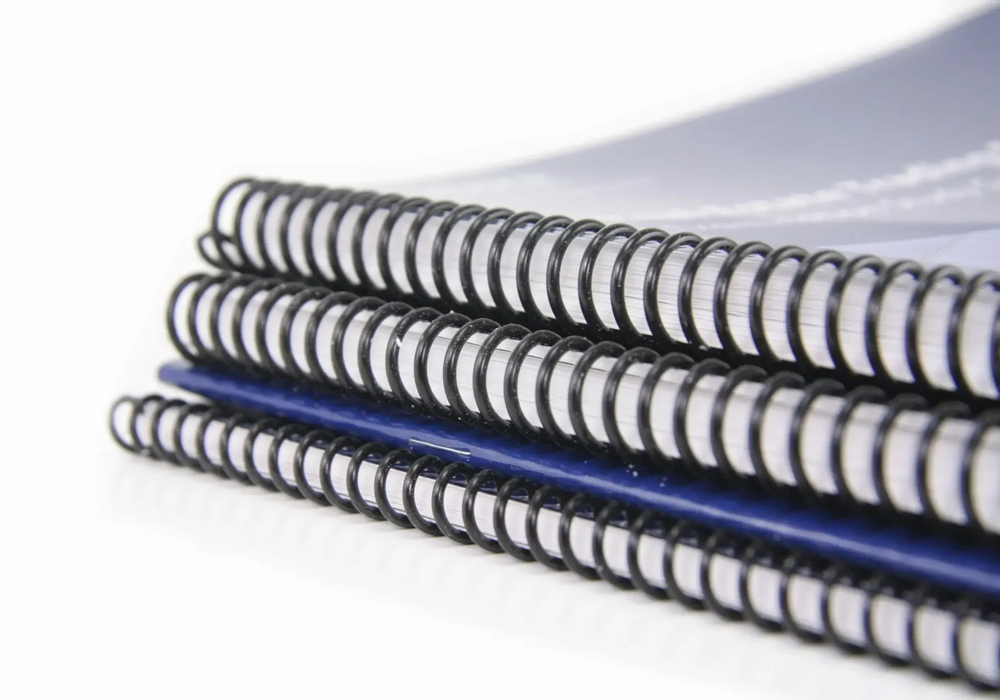A stack of spiral-bound notebooks with white covers.