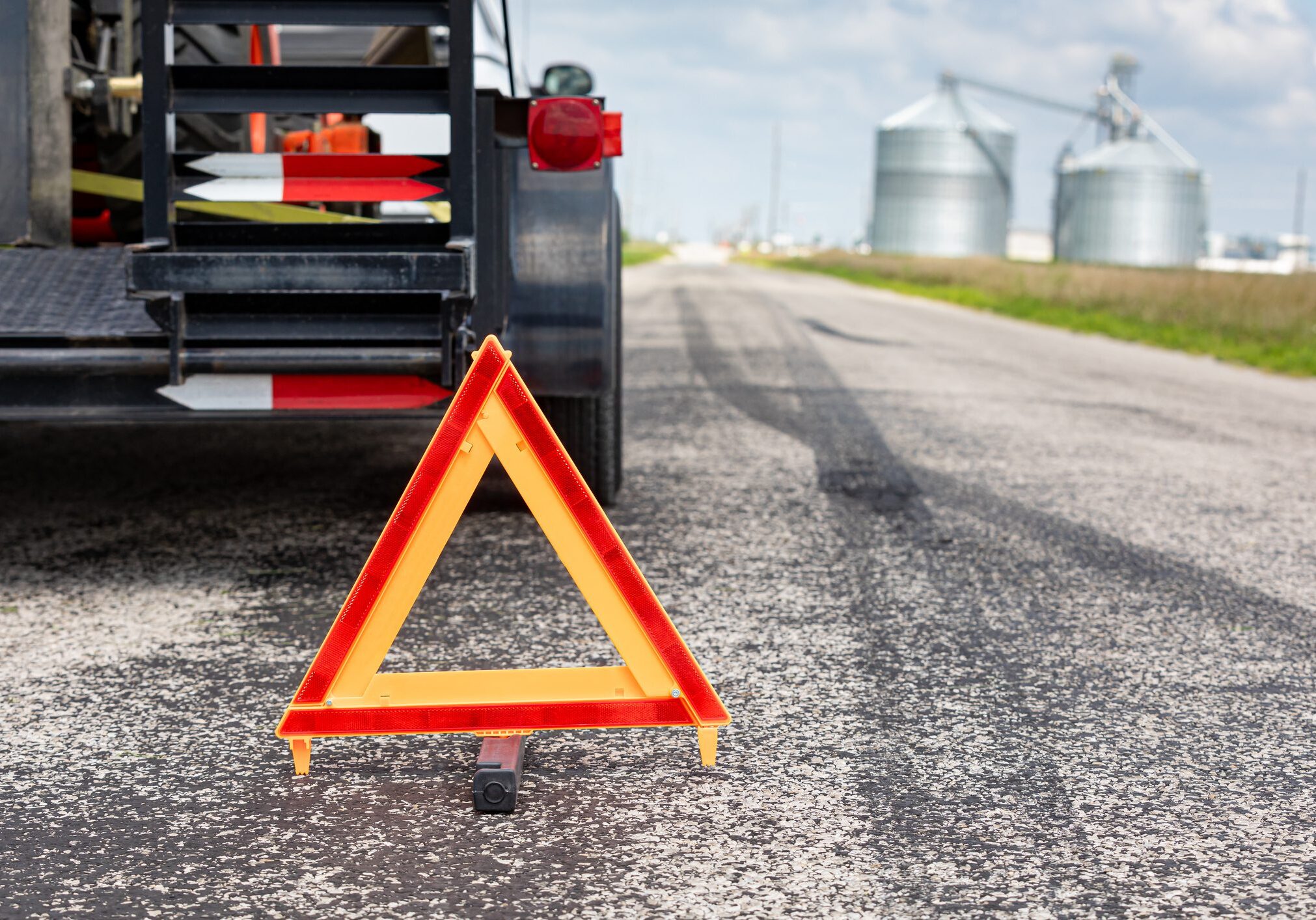 A warning triangle placed behind a stopped truck on a rural road.